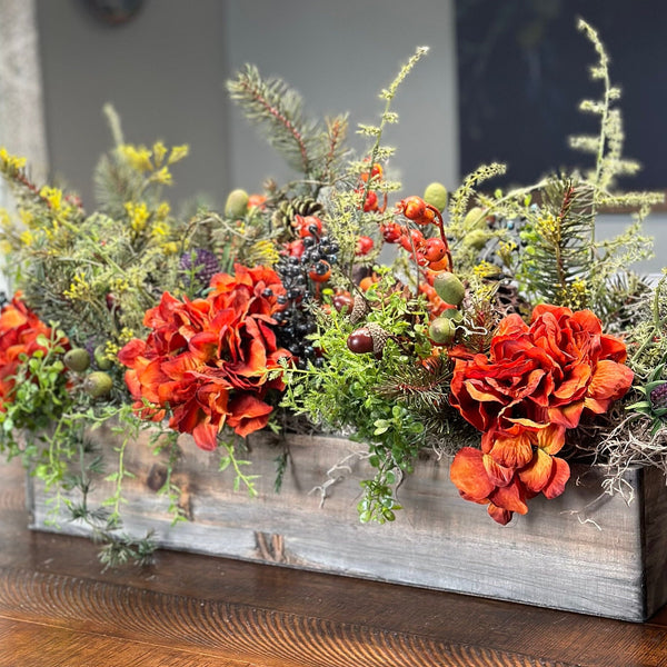 This fall centerpiece is perfect for decorating your table top! It is a grey wash wooden rectangle box 20" long x 9" high by 5" This rustic style arrangement is stunning with  orange hydrangeas nestled in greenery with acorns, pinecones and berries